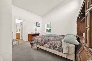 Bedroom featuring light carpet, high vaulted ceiling, and a textured wall