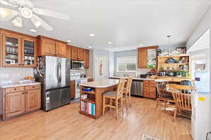 Kitchen featuring brown cabinets, appliances with stainless steel finishes, open shelves, and plenty of natural light