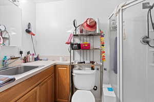 Bathroom with toilet, vanity, and a stall shower