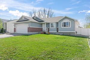 Ranch-style house with a front yard, an attached garage, fence, concrete driveway, and brick siding