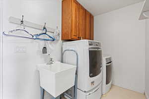 Laundry area with baseboards, washing machine and dryer, a sink, and cabinet space