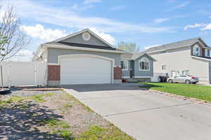 Ranch-style home featuring an attached garage, concrete driveway, brick siding, stucco siding, and a gate