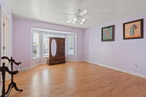 Foyer entrance with visible vents, baseboards, ceiling fan, a textured ceiling, and light wood finished floors