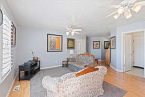 Living area featuring visible vents, light wood-type flooring, a ceiling fan, and plenty of natural light