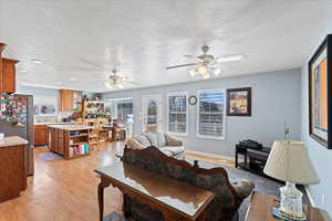 Living room with light wood-type flooring, a textured ceiling, and a ceiling fan