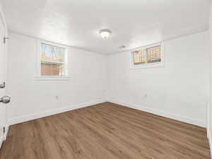 Spare room with baseboards, wood finished floors, and a textured ceiling