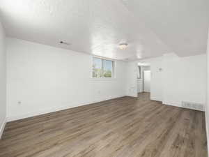 Unfurnished room featuring visible vents, a textured ceiling, and wood finished floors