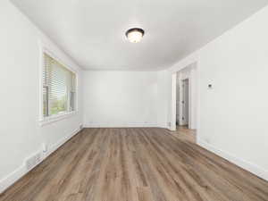 Spare room featuring wood finished floors, baseboards, and visible vents