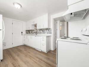Kitchen featuring light countertops, white appliances, light wood-style floors, and under cabinet range hood