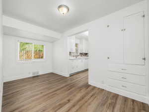 Interior space with visible vents, ensuite bathroom, baseboards, a sink, and light wood-style flooring