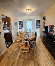 Dining room with baseboards, light wood-type flooring, and a textured ceiling