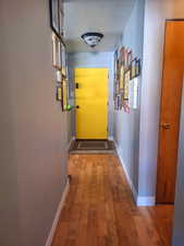 Hall featuring wood-type flooring, baseboards, and a textured ceiling
