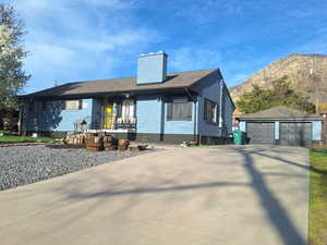 Ranch-style house featuring an outbuilding, a detached garage, brick siding, a chimney, and a mountain view