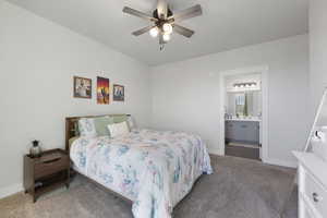 Bedroom with light carpet, ensuite bathroom, baseboards, and a ceiling fan