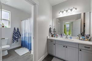 Full bathroom featuring visible vents, baseboards, toilet, vanity, and wood finished floors