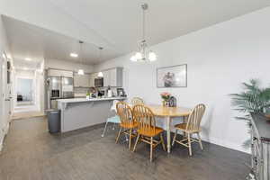 Dining area with recessed lighting, dark wood-style floors, vaulted ceiling, and an inviting chandelier