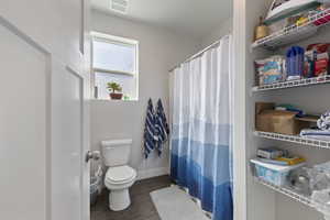 Full bath featuring a shower with curtain, visible vents, toilet, wood finished floors, and baseboards