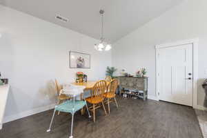 Dining area featuring visible vents, baseboards, an inviting chandelier, wood finished floors, and high vaulted ceiling