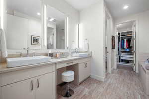 Full bathroom with a sink, a washtub, double vanity, and a spacious closet