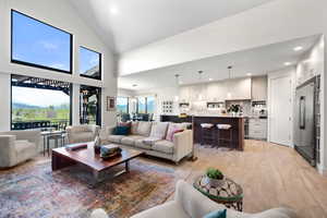 Living room with recessed lighting, lofted ceiling, and light wood finished floors