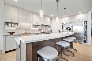 Kitchen with a sink, light wood-style flooring, recessed lighting, tasteful backsplash, and stainless steel built in refrigerator