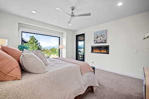 Bedroom featuring a glass covered fireplace, carpet floors, baseboards, and recessed lighting