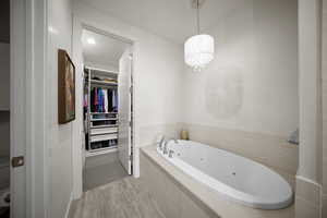 Bathroom with a air jet and whirlpool tub, a chandelier, and a closet with