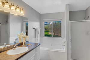 Ensuite Full bath featuring a shower stall, vanity, and a bath
