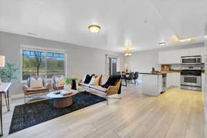 Living area with light wood-style flooring, an inviting chandelier, visible vents, and a wealth of natural light