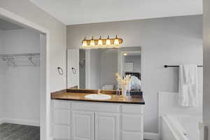 Ensuite Full bath with a bath, a spacious closet, baseboards, and vanity