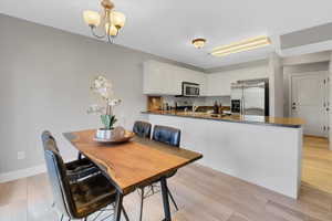Dining area featuring light wood-type flooring, an inviting chandelier, and baseboards