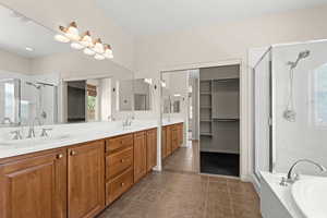 Full bathroom with a stall shower, a garden tub, double vanity, and a sink