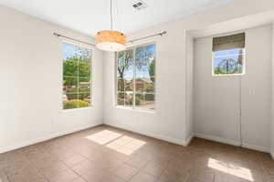 Unfurnished dining area featuring visible vents, a wealth of natural light, and tile patterned flooring