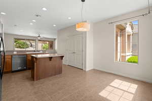 Kitchen featuring light countertops, a kitchen island, visible vents, a kitchen bar, and dishwasher