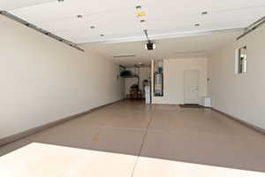 Garage with a garage door opener, baseboards, and gas water heater