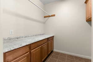 Clothes washing area featuring baseboards and dark tile patterned floors