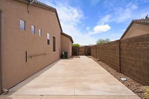 View of property exterior featuring central air condition unit, stucco siding, a gate, a patio area, and fence