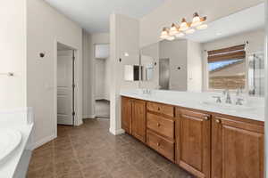 Full bathroom with a sink, a bath, double vanity, and baseboards