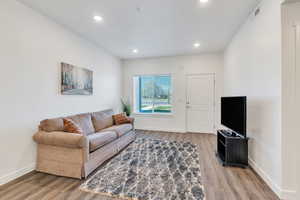 Living room featuring light wood-style flooring, visible vents, baseboards, and recessed lighting