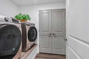 Clothes washing area with dark wood-style flooring, independent washer and dryer, and laundry area
