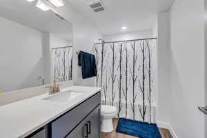 Full bathroom featuring vanity, visible vents, toilet, and wood finished floors