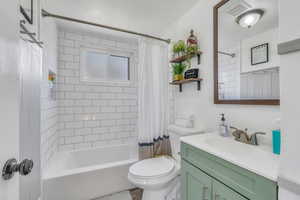 Full bath with shower / bathtub combination with curtain, vanity, visible vents, and toilet