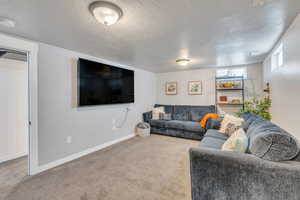 Carpeted living room featuring a textured ceiling and baseboards