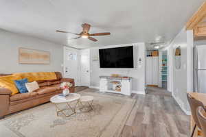 Living area with a textured ceiling, wood finished floors, baseboards, and a ceiling fan