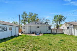 Back of property featuring cooling unit, a yard, and a fenced backyard