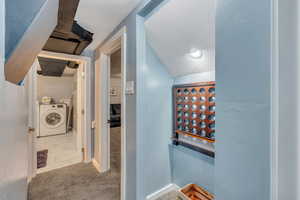 Hall featuring a textured ceiling, baseboards, washing machine and dryer, and carpet floors