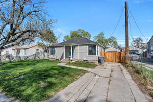 View of front of home featuring roof with shingles, fence, and a front lawn
