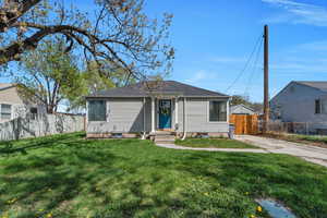 Bungalow-style home featuring a front yard, roof with shingles, driveway, and fence