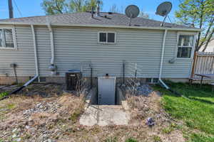 Back of property featuring a shingled roof and cooling unit