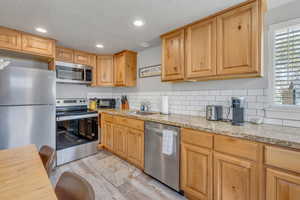 Kitchen with a healthy amount of sunlight, light wood finished floors, a sink, and appliances with stainless steel finishes